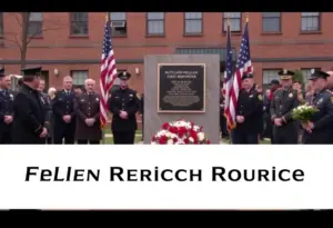 Ceremony honoring Trooper John Doe with solemn attendees in front of a memorial plaque.